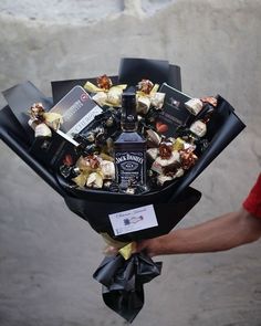 a man holding a bouquet of liquor and chocolates