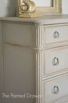 a white dresser with a mirror on top of it next to a wall mounted clock