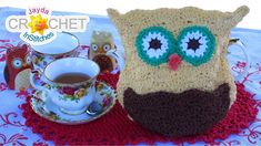 a crocheted owl purse sitting on top of a table next to a cup of coffee