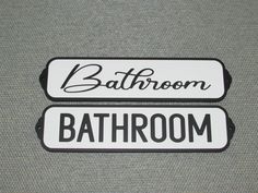 two bathroom signs sitting on top of a gray wall next to another sign that says bathroom