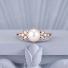 a pearl and diamond ring sitting on top of a white box