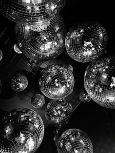 many shiny disco balls hanging from the ceiling in a black and white photo with lights shining on them