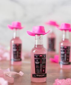 pink bottles with hats on them sitting on a table