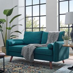 a living room scene with focus on the blue couch and rug, which is next to a large window