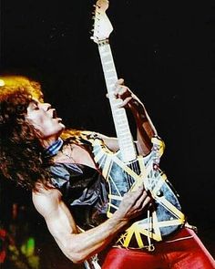 a man with long hair playing an electric guitar