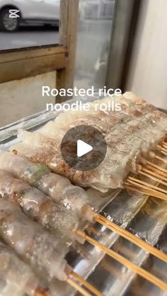 food is being cooked on the grill with chopsticks in front of it and an advertisement that reads roasted rice noodles noodle rolls