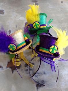 two mardi gras hats are sitting on top of each other, with feathers