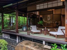 an outdoor room with chairs and tables on the deck in front of some trees, rocks and plants