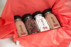 four jars filled with different types of food on top of a red paper wrapper