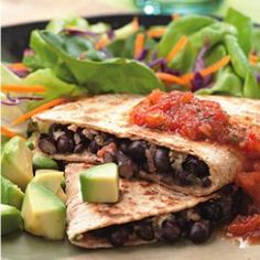 two quesadillas with black beans and avocado are on a plate