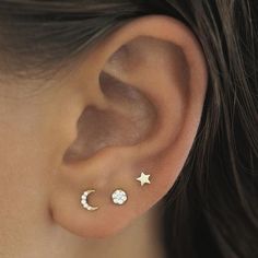 a close up of a person's ear with three stars and moon studs