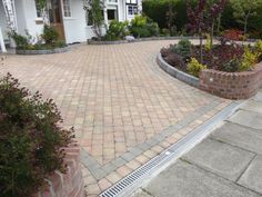 a brick driveway surrounded by plants and flowers