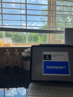 a laptop computer sitting on top of a desk next to an award winning window sill