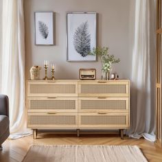 a living room with two pictures on the wall and a dresser in front of it