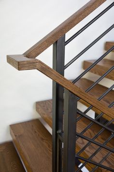 a wooden and metal stair case next to a white wall