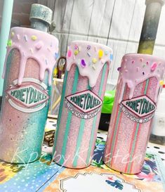 three pink and blue frosted donuts sitting on top of a table next to each other