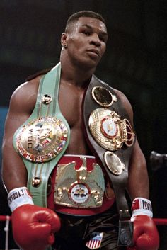 the professional boxer stands in his boxing ring with his belts around his waist and hands on his hips