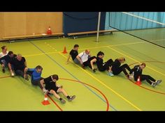 a group of people sitting on top of a green floor next to each other in front of an orange cone