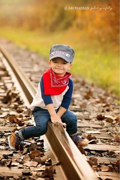 a young boy is sitting on the railroad tracks