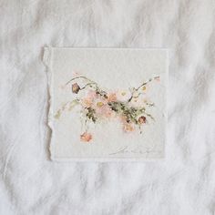 a piece of paper with flowers on it sitting on top of a white cloth covered tablecloth