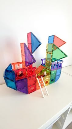 there is a sculpture made out of plastic blocks on the table next to a ladder