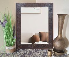 a mirror sitting on top of a table next to a vase