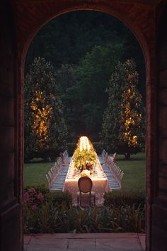 an outdoor dining table is lit up at night with lights shining down on the tables