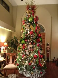 a decorated christmas tree in the middle of a living room with red, green and gold ornaments