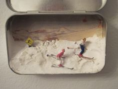 two figurines are in a tin with snow