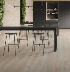 a modern kitchen with wood flooring and black counter tops, along with bar stools