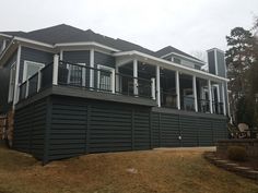 a large gray house sitting on top of a lush green field