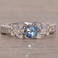 a blue and white diamond ring sitting on top of a wooden table