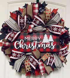 a christmas wreath hanging on the front door decorated with burlocks and plaid ribbon