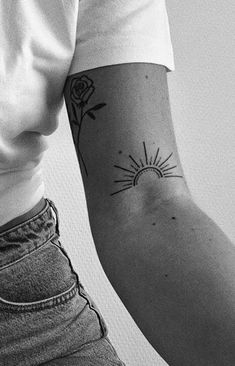 a person with a tattoo on their arm and the sun behind them, in black and white