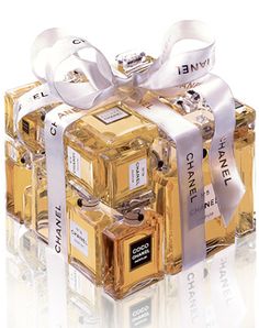 three gold cubes with white ribbons tied around the top and one has a bow on it