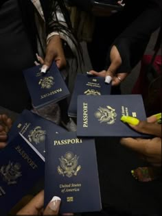 several people are holding their passports in one hand and pointing them at something on the other