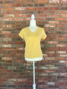 "Description: Awesome sunny muted yellow V neck short sleeve jersey tee shirt from the 70s with a cute floral embroidered detail at the left side of the chest. pulls on overhead. Label: no brand labeled Size:  tag reads Medium, fits true. Material: 65% polyester 35% cotton , supersoft great quality jersey. Condition: Excellent vintage condition! very gently used, no flaws of any kind, ready to wear! Measurements: Length:  23\" Bust:  40\" Waist: 36\" Hips: 38\" * I SHIP DAILY* **check out my shop+ for more +unique +on trend +quality+ vintage" Muted Yellow, Sunny Yellow, Workout Tshirts, T Shirt And Shorts, Jersey Tee, V Neck Tee, Size Tag, Womens Clothing Tops, Sunnies