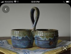 two cups sitting on top of a yellow and blue cloth next to a wooden table