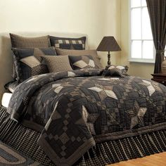 a black and brown quilted comforter set on top of a bed next to a lamp