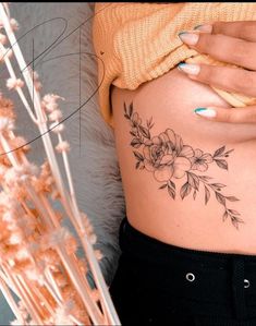 a woman's stomach with flowers and leaves on her belly, next to dried grass