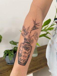 a woman's arm with a vase tattoo on it