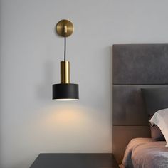 a bedroom with a bed, night stand and lamp on the wall next to it