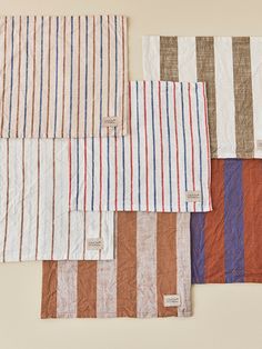 four different colors of striped linens on a white tablecloth, one in red, one in blue and the other in brown