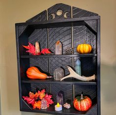 a black shelf with pumpkins, candles and other decorations