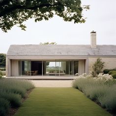 the house is surrounded by tall grass and lavender bushes, with an open patio area on one side