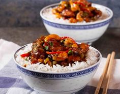 two bowls filled with rice and meat on top of a table next to chopsticks