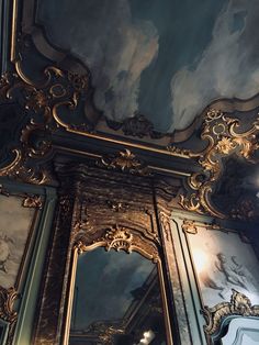 an ornately decorated mirror in the middle of a room with blue and gold walls