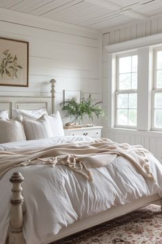 a bed with white linens and pillows in a bedroom next to two large windows