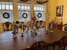 a dining room table with christmas decorations and wreaths on the window sill above it