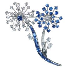 A vintage Oscar Heyman sapphire, diamond and platinum flower brooch, in an abstract design of two flowers, one with a round faceted sapphire, in the centre of round brilliant cut diamond set petals, in claw settings and a baguette-cut sapphire stem, in channel settings and the other with a round brilliant cut diamond, in the centre of round faceted sapphire petals, in claw settings and a baguette-cut diamond stem, in channel settings, with marquise diamond set leaves, in claw settings, with flower engraving on the back of the flower centres and dot and dash engraving on stems, mounted in platinum, numbered 69671, stamped PLAT, Circa 1964. Accompanied by a letter of authenticity, from Oscar Heyman, stating that the brooch was manufactured by Oscar Heyman and Brothers, circa 1964; giving the Dot And Dash, Flower Engraving, Two Flowers, Flower Center, Marquise Cut Diamond, Baguette Cut Diamond, Marquise Diamond, Diamond Set, Baguette Cut